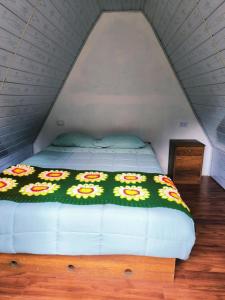 a bed with a green blanket with flowers on it at EcoSereno Salkantay Huts Chaullay in Santa Teresa