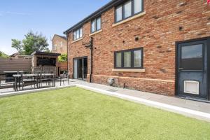 a brick building with a patio with a grass yard at Modern Large 4-Bed Property sleeps 10 in Abergele in Abergele