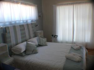 1 dormitorio con 1 cama grande con sábanas y almohadas blancas en Breakaway Apartment with Balcony, en Yzerfontein
