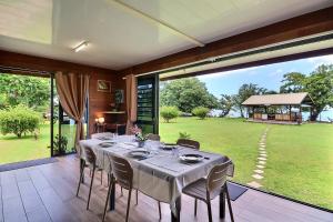 a dining room with a table and a large window at Fare Heimery - Private Lagoon Beach in Haapiti