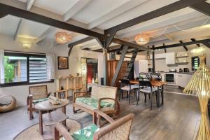 a living room with tables and chairs and a kitchen at Fare Vainina Private beach - Golf in Moorea