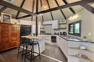 a kitchen with white cabinets and a counter with stools at Fare Vainina Private beach - Golf in Moorea