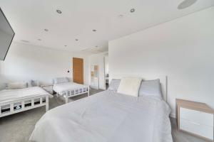 a white bedroom with two beds and a couch at Modern Large 4-Bed Property sleeps 10 in Abergele in Abergele