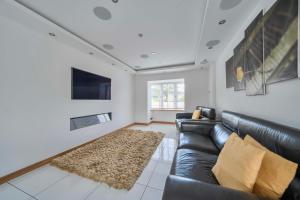 a living room with a black leather couch and a rug at Modern Large 4-Bed Property sleeps 10 in Abergele in Abergele