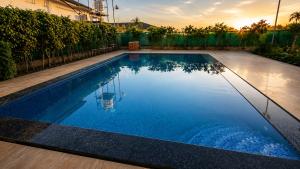 a swimming pool with blue water in a backyard at Vijay Laxmi Farm House in Manjhāoli