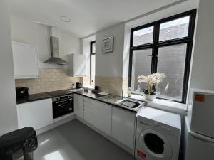 a kitchen with a washing machine and a window at Cosy flat in central Cardiff Bay in Cardiff