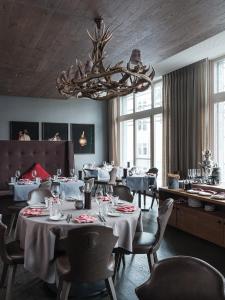 a dining room with tables and chairs and a chandelier at AMERON Davos Swiss Mountain Resort in Davos