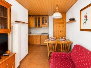 a kitchen with a table and a red couch at Residence Borgo Al Sole in Sappada