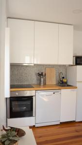 a kitchen with white cabinets and a white dishwasher at Apartamentos Aurea - Sesimbra in Sesimbra