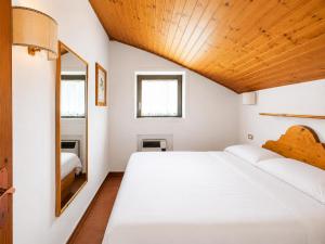 a bedroom with a large white bed and a mirror at Residence Borgo Al Sole in Sappada