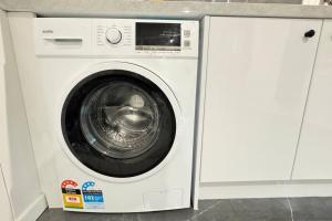a white washing machine sitting in a white cabinet at Pool House with 3 BDR 2 AC in Marsden