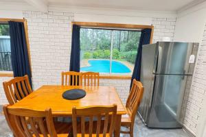 a kitchen with a wooden table and a refrigerator at Pool House with 3 BDR 2 AC in Marsden