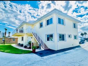 a large white house with a staircase at Steps to Private Beach Access King Beds in Ormond Beach