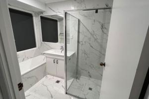 a white bathroom with a shower and a sink at SPA House 4 BDR 5 beds Master with AC) in Boronia Heights +22 photos