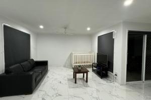 a living room with a black couch and a table at SPA House 4 BDR 5 beds Master with AC) in Boronia Heights