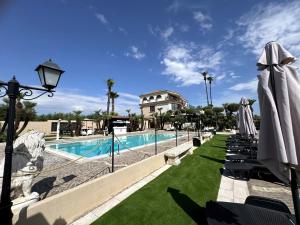 a resort with a swimming pool with lawn chairs and umbrellas at Le Tre Rose di Metta in Cerignola
