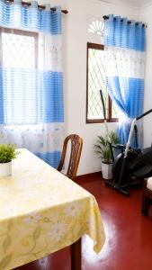 a dining room with a table and chairs and windows at පසන් නිවස Pasan Niwasa Homestay Bandarawela in Bandarawela