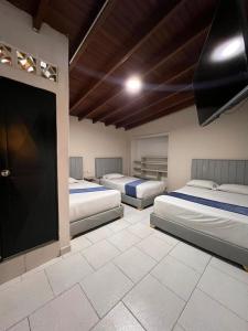 three beds in a room with a flat screen tv at Hotel San Juan 70 Express Medellin in Medellín