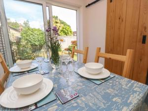 a table with plates and bowls and glasses on it at Camellia Cottage in Wimborne Minster