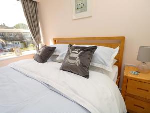 a bedroom with a white bed with pillows and a window at Camellia Cottage in Wimborne Minster