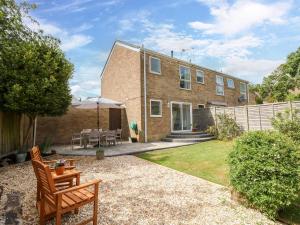 a brick house with a patio and a table at Camellia Cottage in Wimborne Minster