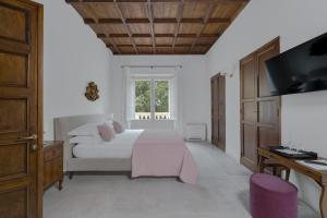 a white bedroom with a bed and a tv at Villa Tuzzo in Lecce