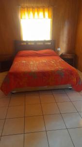 a bedroom with a bed with a red comforter and a window at Camping Las Torcacitas in Yerbas Buenas