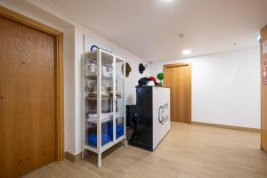 a room with a refrigerator and a shelf with dishes at Central Suítes 3 in São João da Madeira