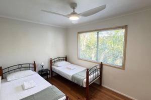 two beds in a room with a window at Pool house for BIG Groups with Free parking in Marsden