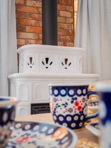 a table with cups and plates on a table with a fireplace at Bugiem i Miodem in Siemiatycze +56 photos