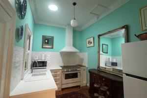 a kitchen with blue walls and a sink and a refrigerator at Oscar's Place in Yass