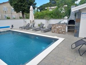 a swimming pool with chairs and an umbrella at Apartmani Sidro in Privlaka