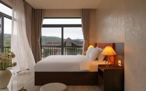 a bedroom with a bed and a large window at Velora Hotel DaLat in Xuan An