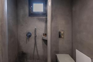 a bathroom with a shower with a toilet and a window at Aerial Villas in Imerovigli +13 photos