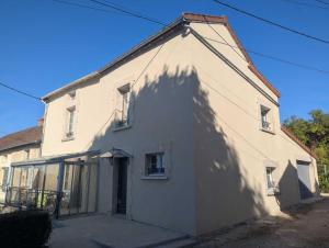 a white house with a large shadow on the side of it at Gîte le saint goth in Bricon