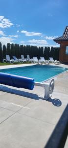 a swimming pool with a blue pool noodle next to some chairs at Chatki Niwki u Zbója in Krościenko