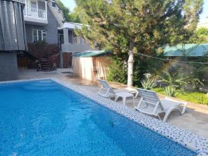 a swimming pool with two white chairs next to a house at Дача Уют Чарвак Узбекистан in Chorwoq