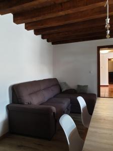 a living room with a brown couch and white chairs at La Casa nel Sole in Savogna