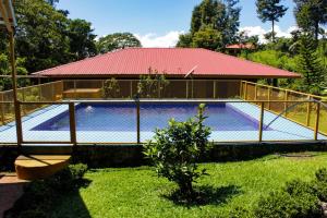 a swimming pool with a building with a red roof at Quinta La Carmencita in Santa Elena