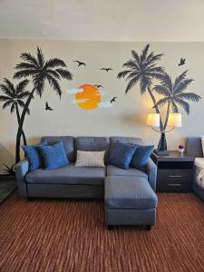 a living room with a couch and palm trees on the wall at Oceanview Room at Landmark Resort in Myrtle Beach
