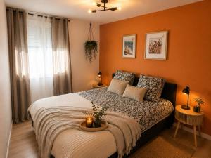 a bedroom with orange walls and a bed with two tables at Le cocon du lac in Montargis