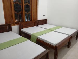 a group of three beds in a room at East HOME Kalmunai in Kalmunai