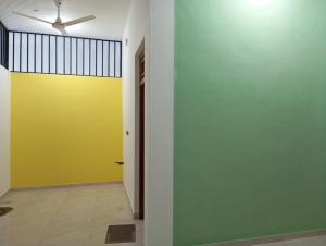 a hallway with a yellow wall and a ceiling fan at East HOME Kalmunai in Kalmunai