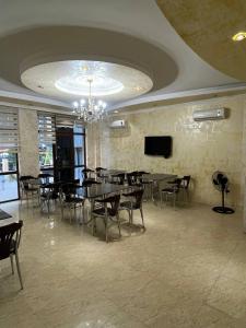 a dining room with tables and chairs and a television at Nelly Hotel in Batumi