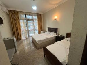 a hotel room with two beds and a window at Nelly Hotel in Batumi