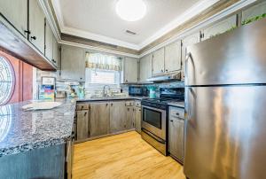 a kitchen with a stainless steel refrigerator and wooden cabinets at Turtle-ly Beachin' - KDH MP 6, Ocean View, Beach 165 Yds, Sound Access, Year Round Flex Stays in Kill Devil Hills