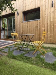 two yellow chairs and a table in front of a building at Maisonnette d'architecte face nature, 15min de Tours in Charentilly +1 photo