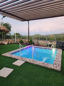a swimming pool with awning and green grass at Cozy Cabin in Cumbres del Nacimiento, La Unión Sur in Conchagua