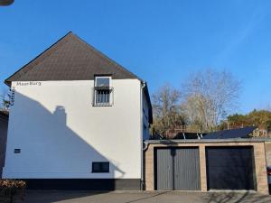 a white house with a black roof at Cottage MaarBurg in Ulmen