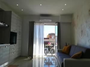 a living room with a blue couch and a window at Sikelia home in Giardini Naxos